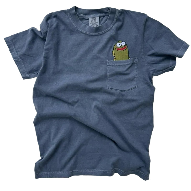 Blue t-shirt with a cartoon character on the chest pocket against a light gray background